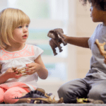 one child sharing an elephant toy with another child