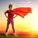 Girl with red cape looking at sunrise