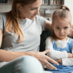 Mother with one arm around child speaking to daughter