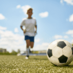 camera focus on soccer ball fuzzy background with boy in soccer uniform